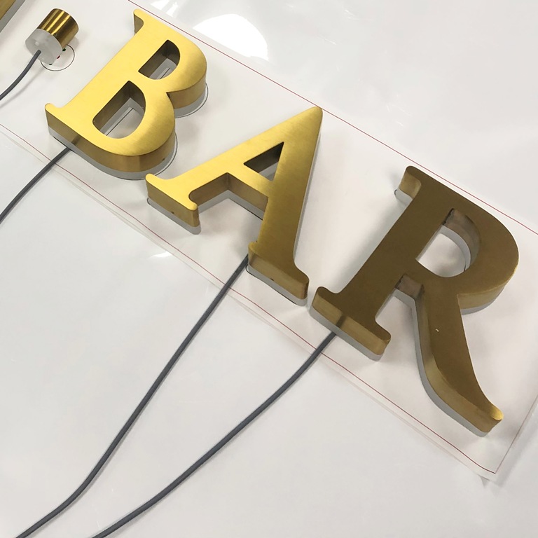 Lettres BAR lumineuses en relief avec finition laiton doré