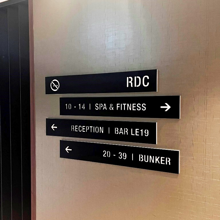 Alt : Signalétique directionnelle noire pour réception, spa, fitness et chambres d’hôtel