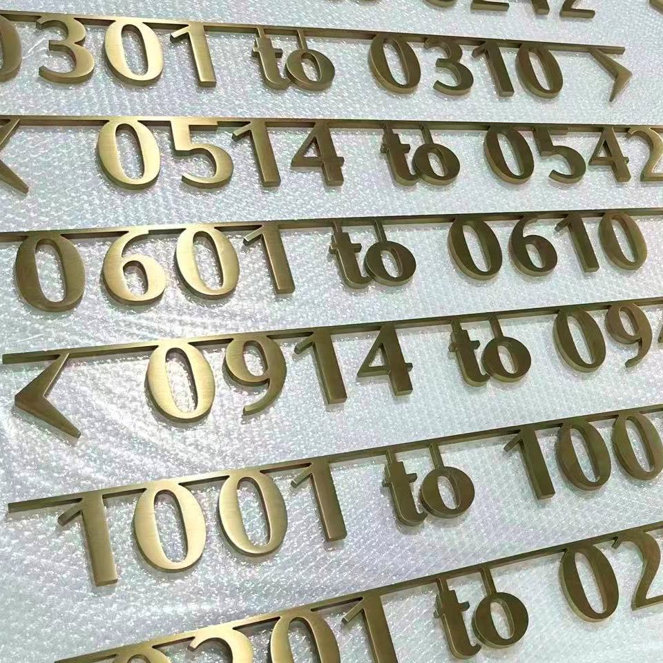 Alt : Signalétique directionnelle dorée avec numéros de chambres d’hôtel