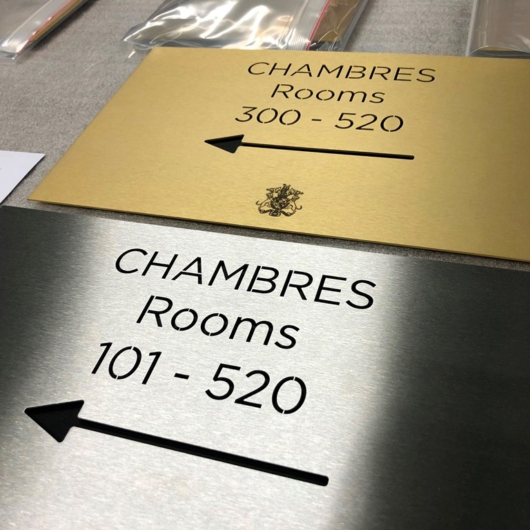 Alt : Plaques directionnelles en laiton doré et inox brossé pour chambres d’hôtel